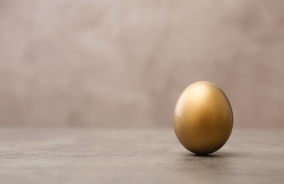 Photo of One shiny golden egg on table, space for text