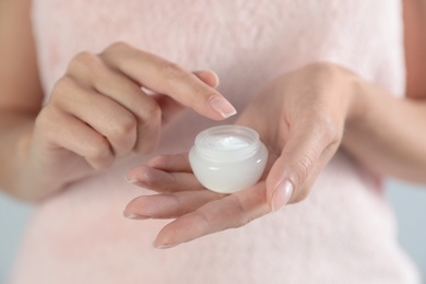 Photo of Young woman holding jar of cream, closeup