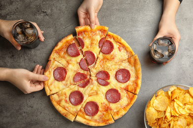 Women taking tasty pepperoni pizza at grey table, top view