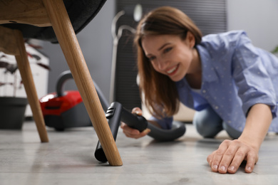 Young woman using vacuum cleaner at home