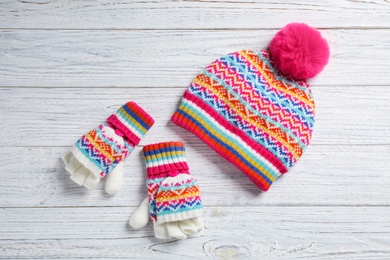 Warm knitted hat and mittens on white wooden background, flat lay