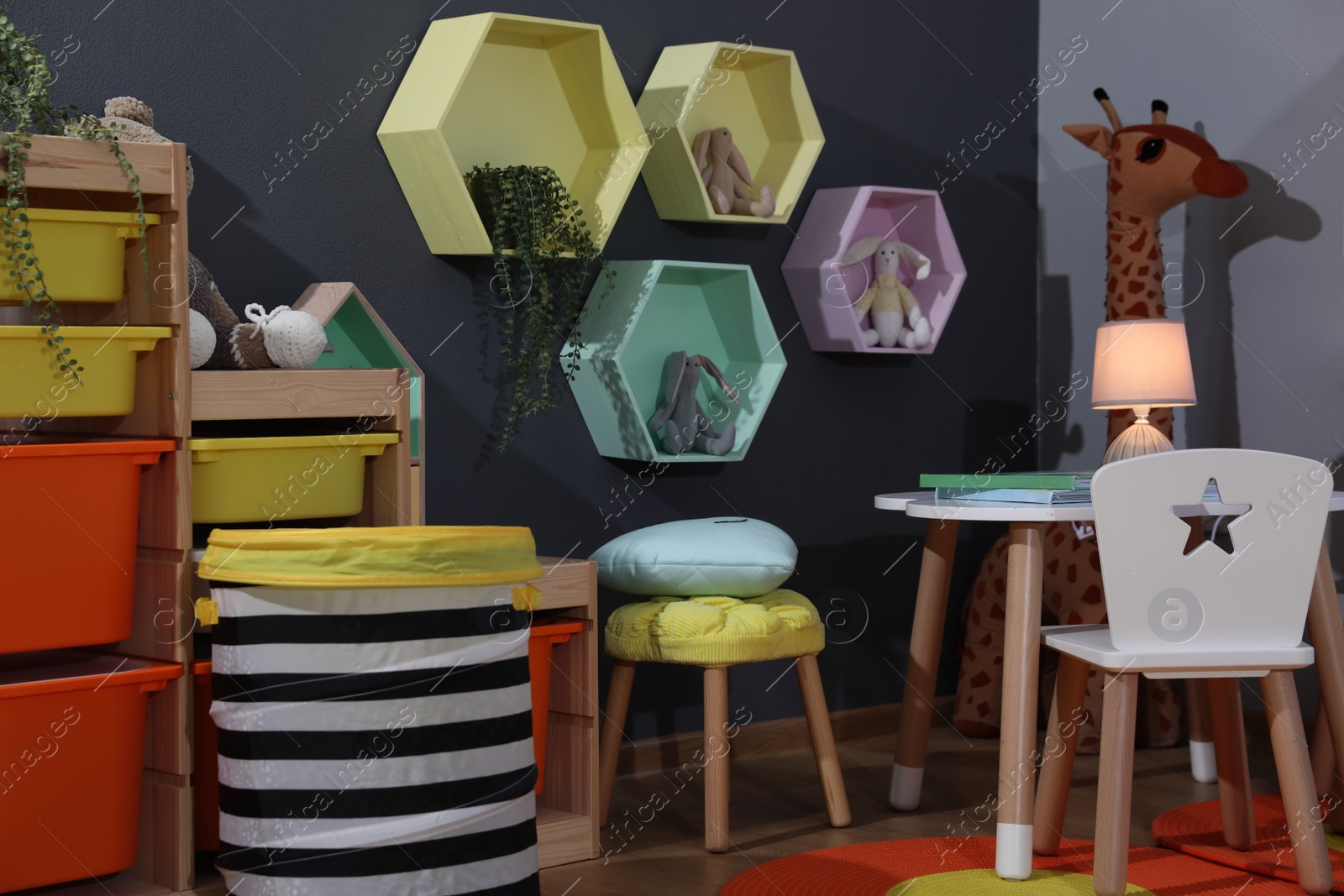 Photo of Stylish child room interior with modern furniture, toys and hexagon shaped shelves