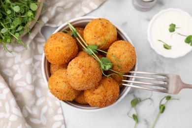 Bowl of delicious fried tofu balls with pea sprouts and sauce on white marble table, flat lay