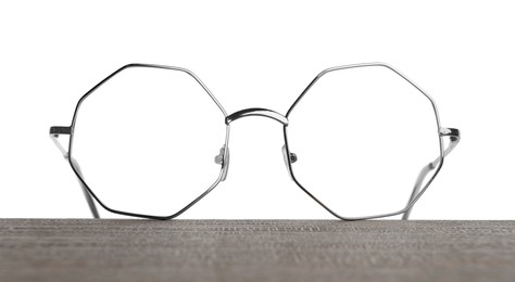 Photo of Stylish glasses with metal frame on wooden table against white background