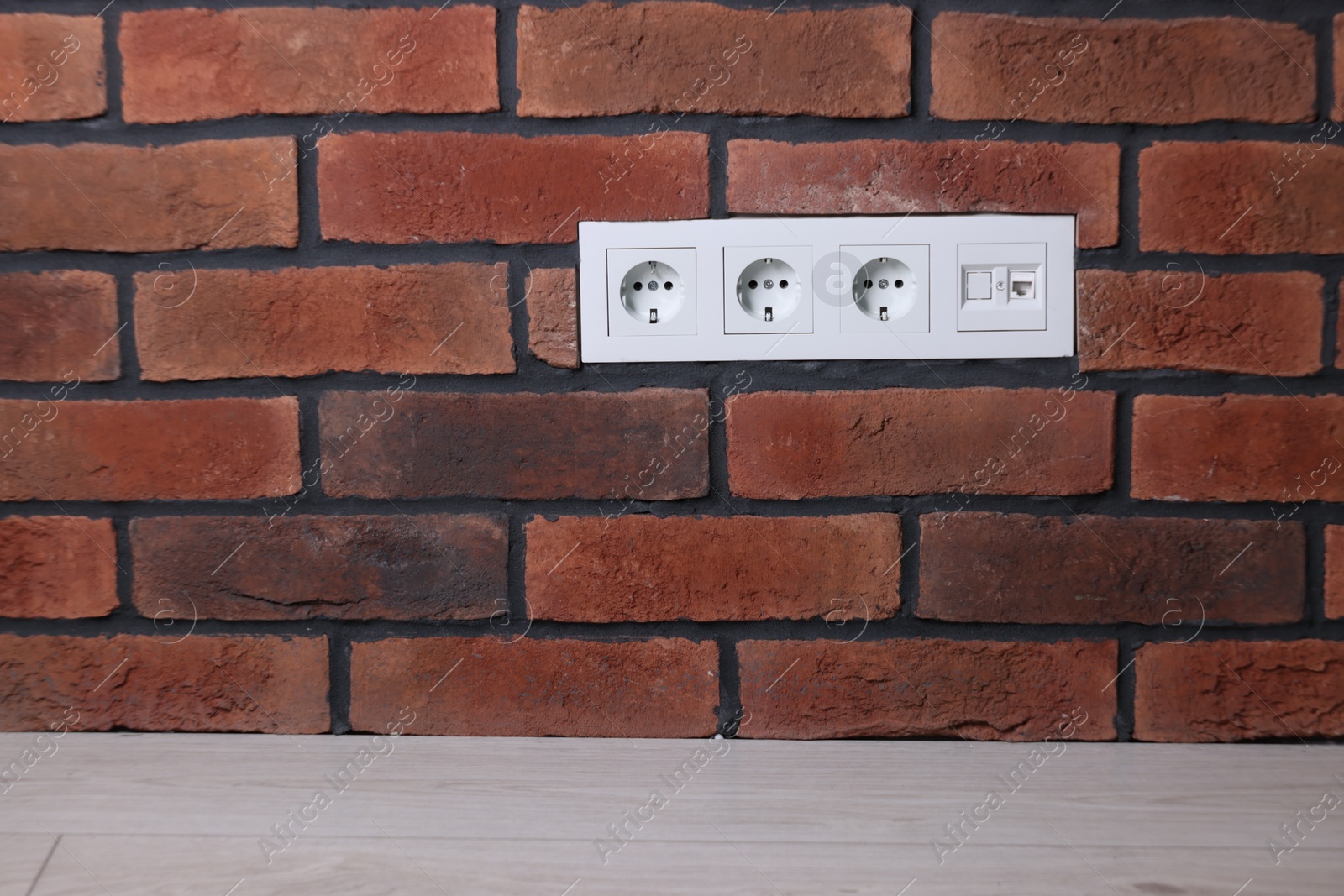Photo of Electric power sockets on brick wall indoors