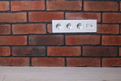 Electric power sockets on brick wall indoors