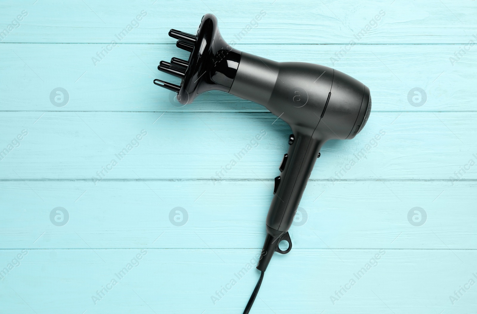 Photo of Hair dryer on light blue wooden table, top view. Professional hairdresser tool