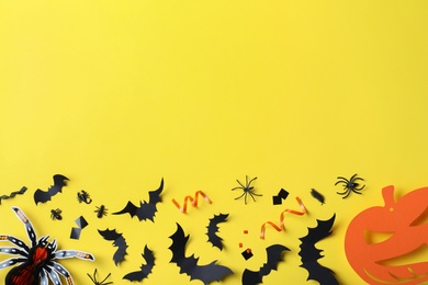 Photo of Halloween decor elements on yellow background, flat lay. Space for text