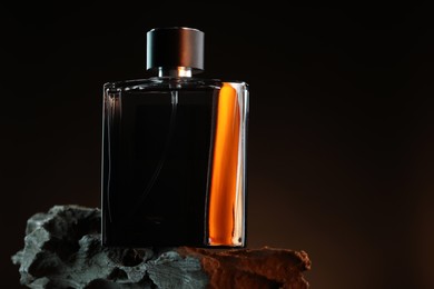 Photo of Luxury men`s perfume in bottle against dark background, space for text