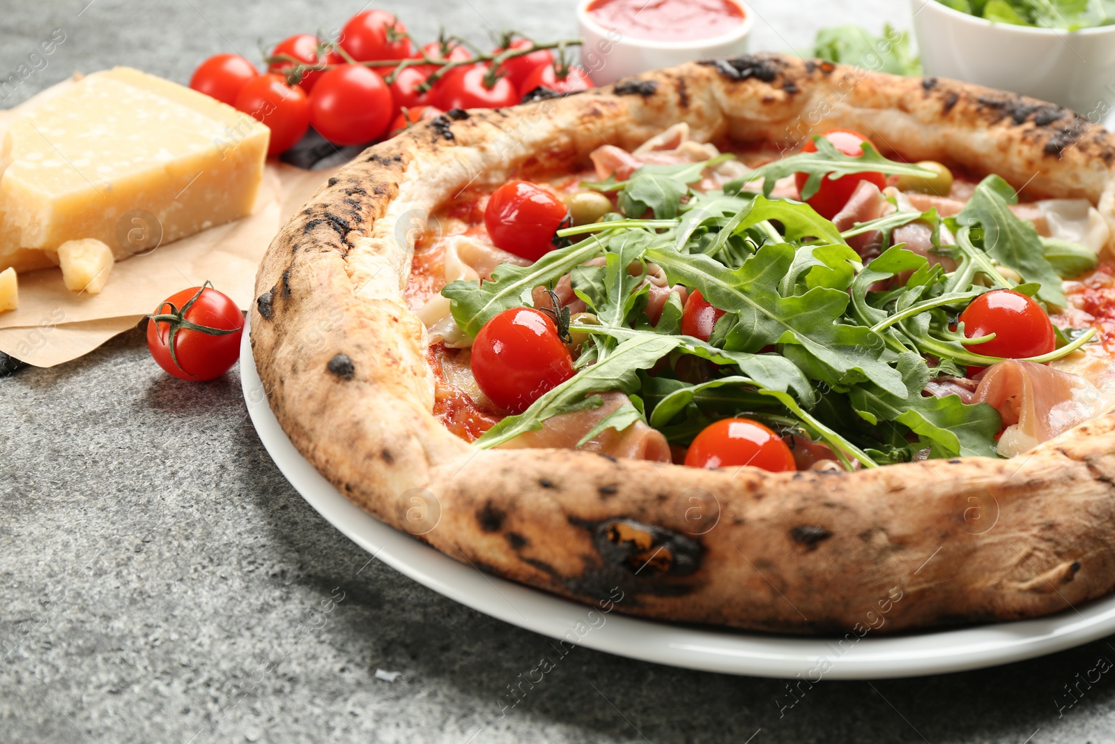 Photo of Tasty pizza with meat and arugula on grey table, closeup