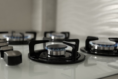 Photo of Gas burners with blue flame on modern stove, closeup