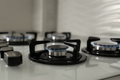 Gas burners with blue flame on modern stove, closeup