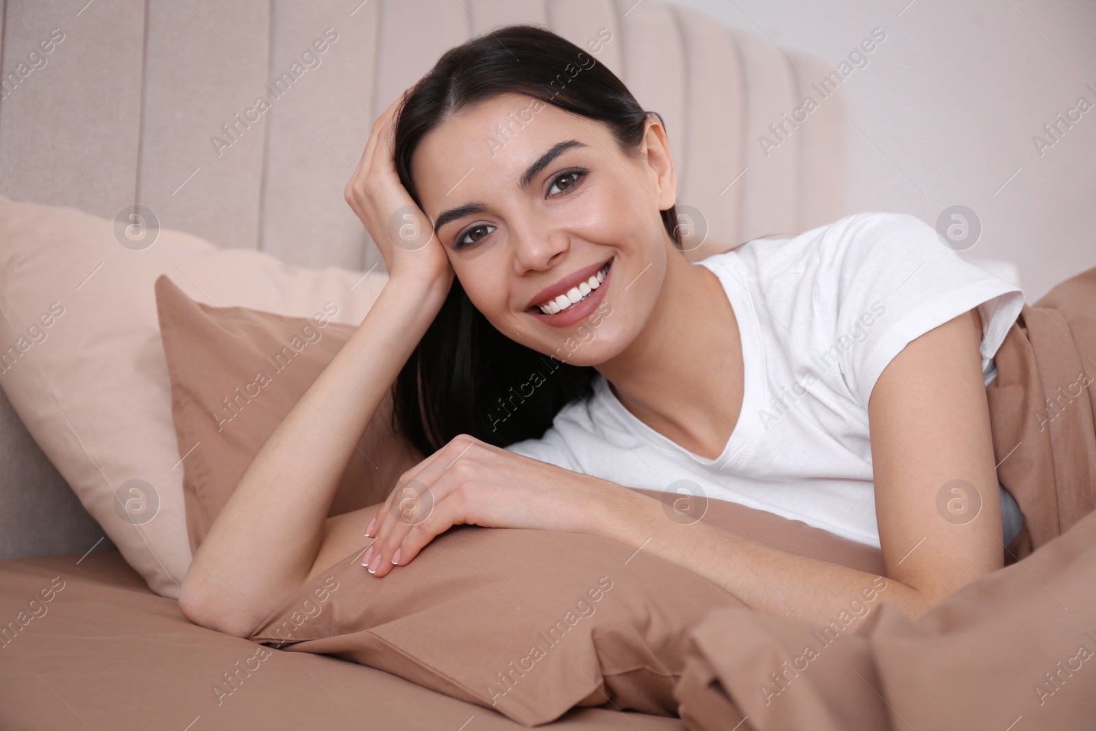 Photo of Woman lying in comfortable bed with beige linens