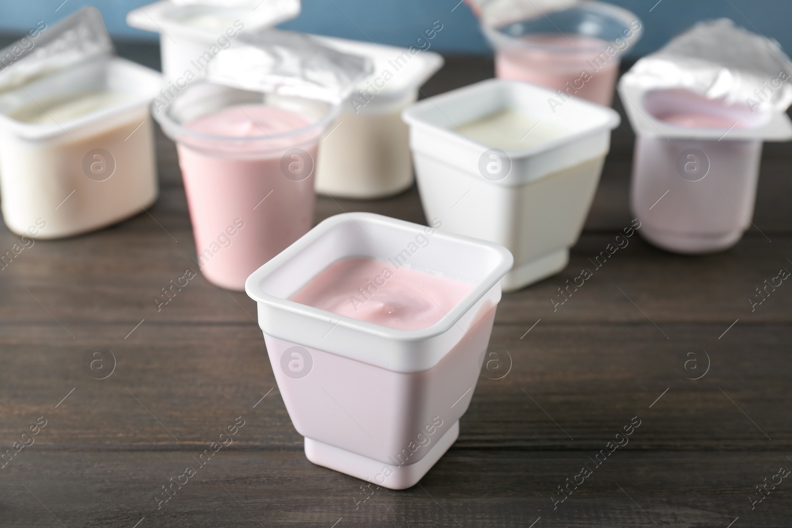 Photo of Plastic cups with tasty yogurt on wooden table