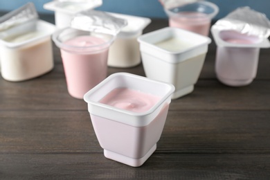 Photo of Plastic cups with tasty yogurt on wooden table