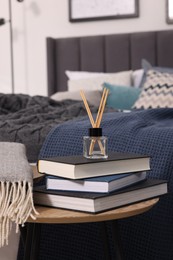 Photo of Aromatic reed air freshener, books and plaid on table, space for text