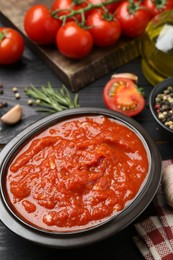 Homemade tomato sauce in bowl on black table, closeup