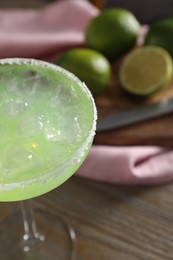 Delicious Margarita cocktail in glass on wooden table, closeup