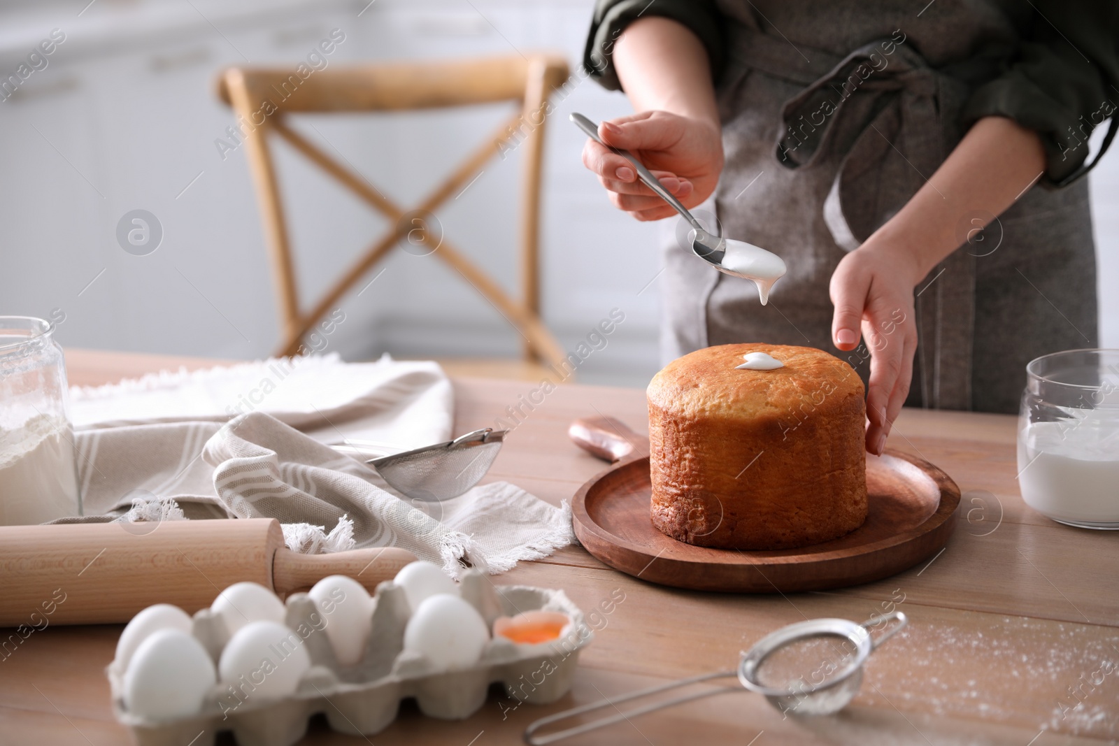 Photo of Young woman with traditional Easter cake in kitchen, closeup. Space for text