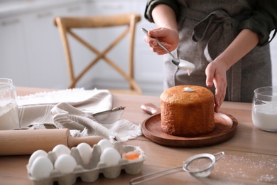 Photo of Young woman with traditional Easter cake in kitchen, closeup. Space for text