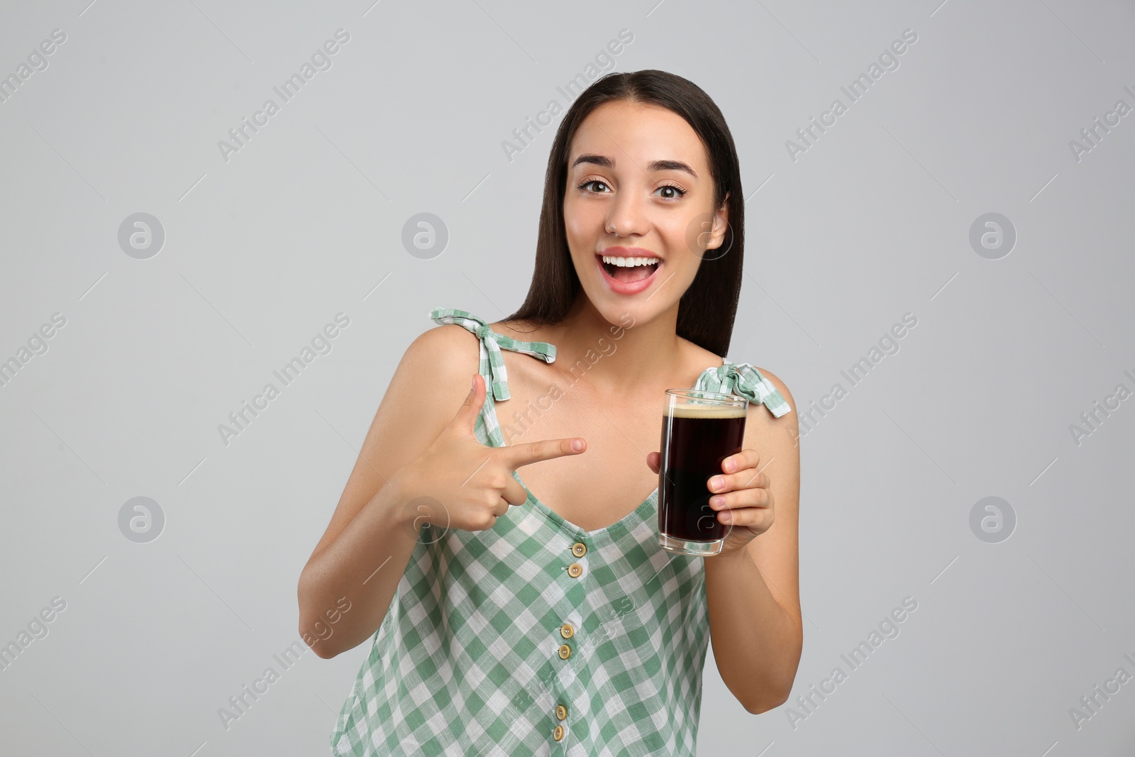 Photo of Beautiful woman with cold kvass on light grey background. Traditional Russian summer drink