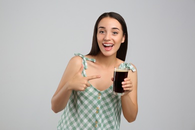 Beautiful woman with cold kvass on light grey background. Traditional Russian summer drink