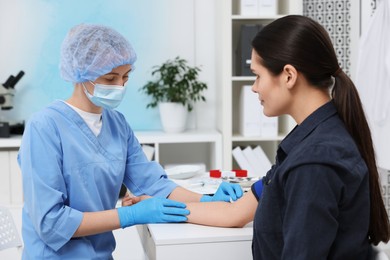 Photo of Laboratory testing. Doctor taking blood sample from patient at white table in hospital