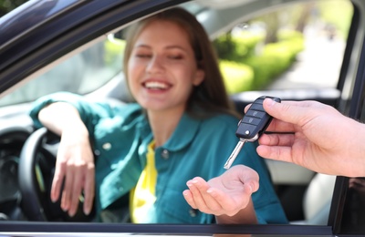 Image of Salesperson giving car key to customer, focus on hands