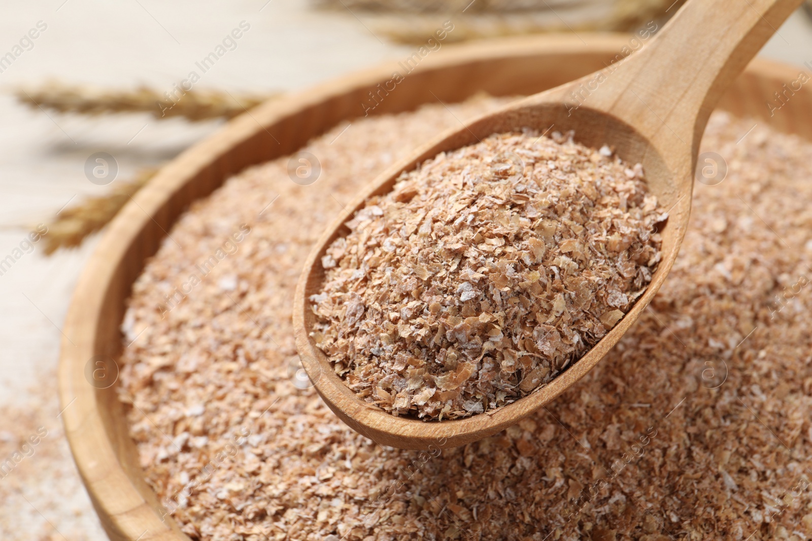 Photo of Spoon of wheat bran above bowl, closeup