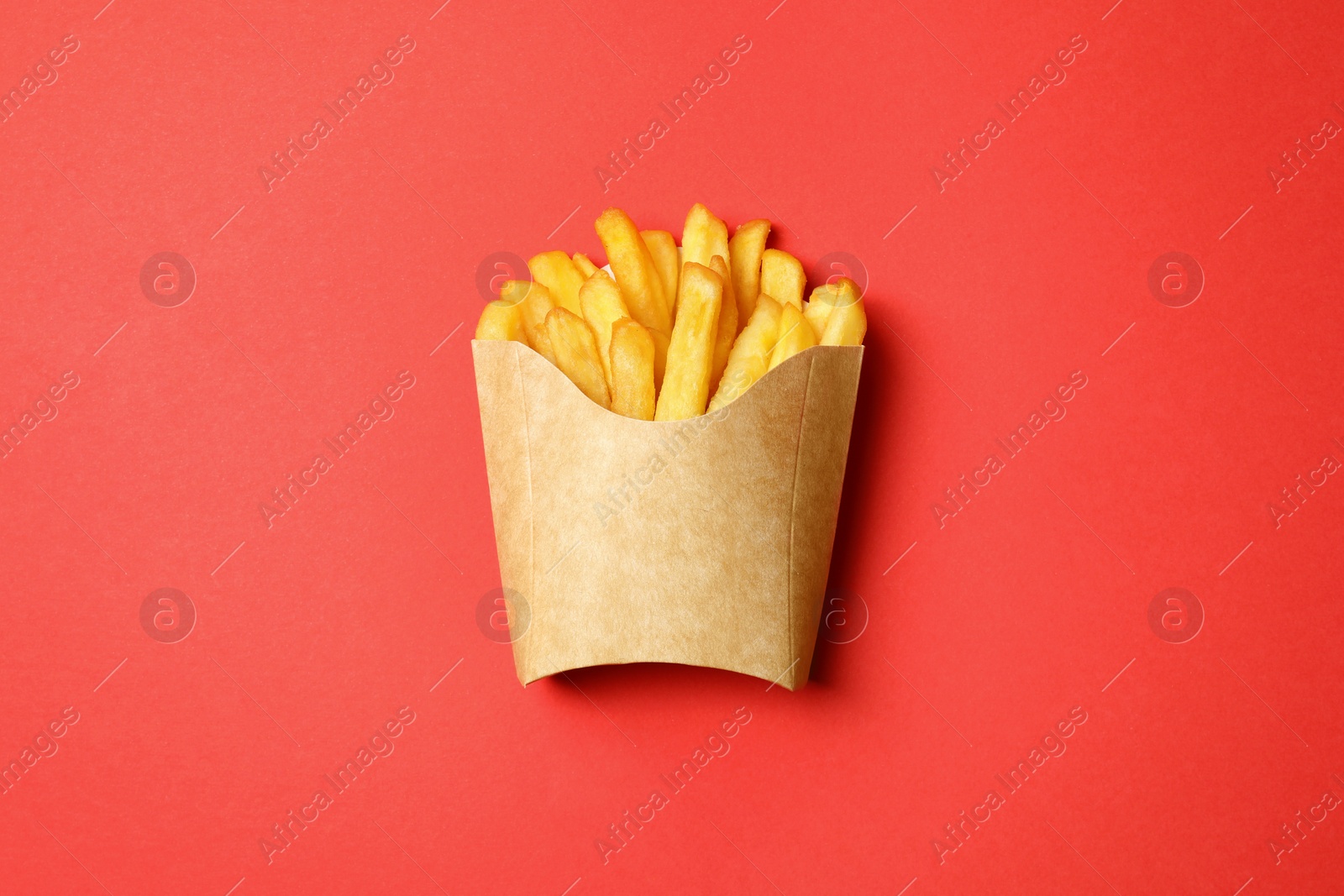 Photo of Paper cup with French fries on red table, top view