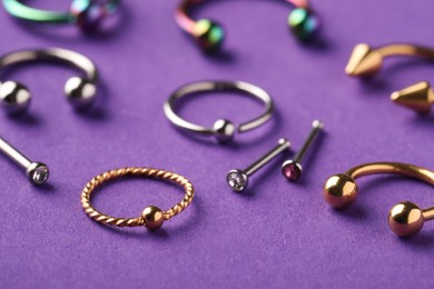 Photo of Stylish jewelry for piercing on violet background, closeup