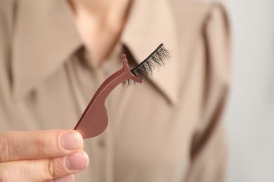 Woman holding tweezers with magnetic eyelashes, closeup