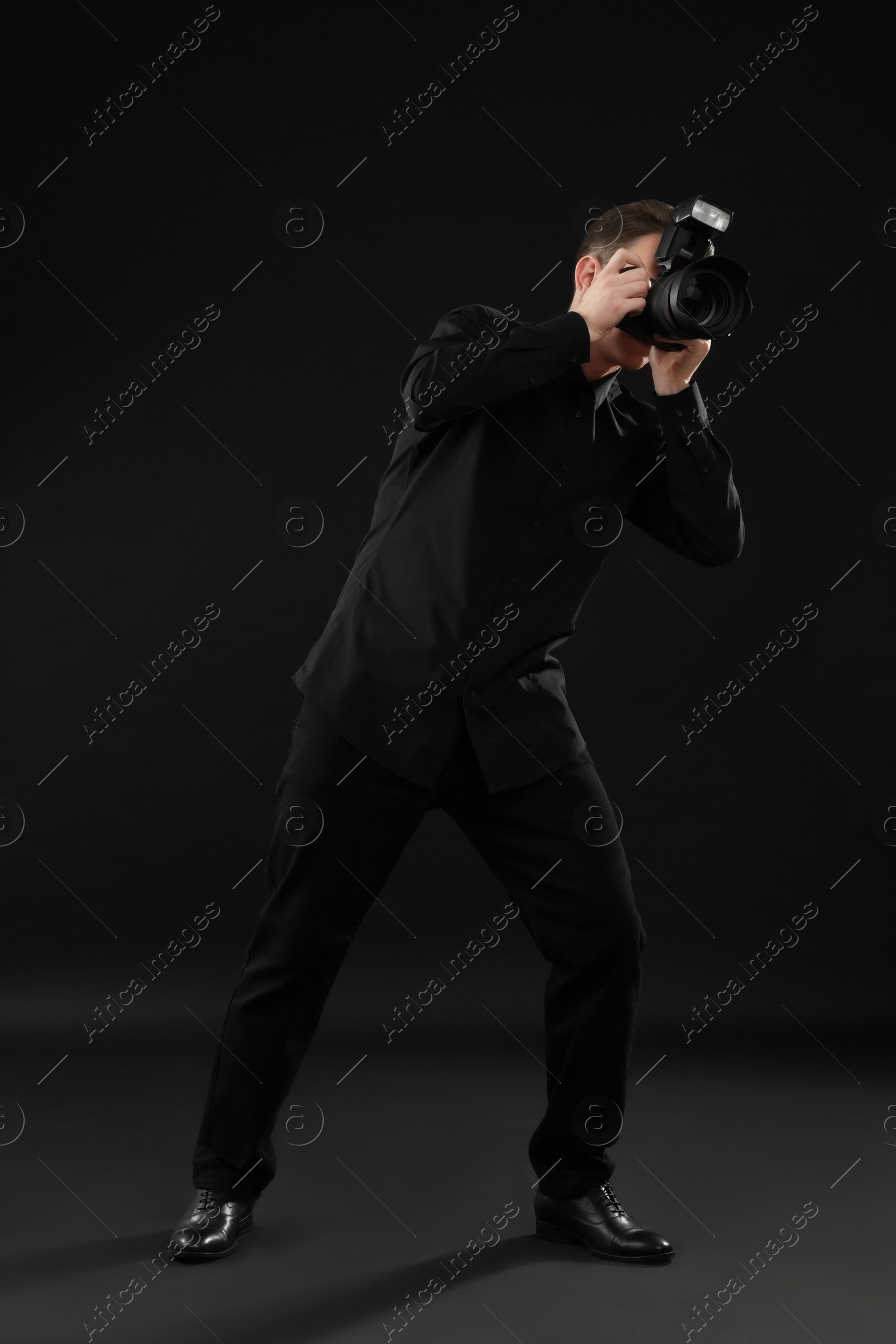 Photo of Professional photographer taking picture on black background