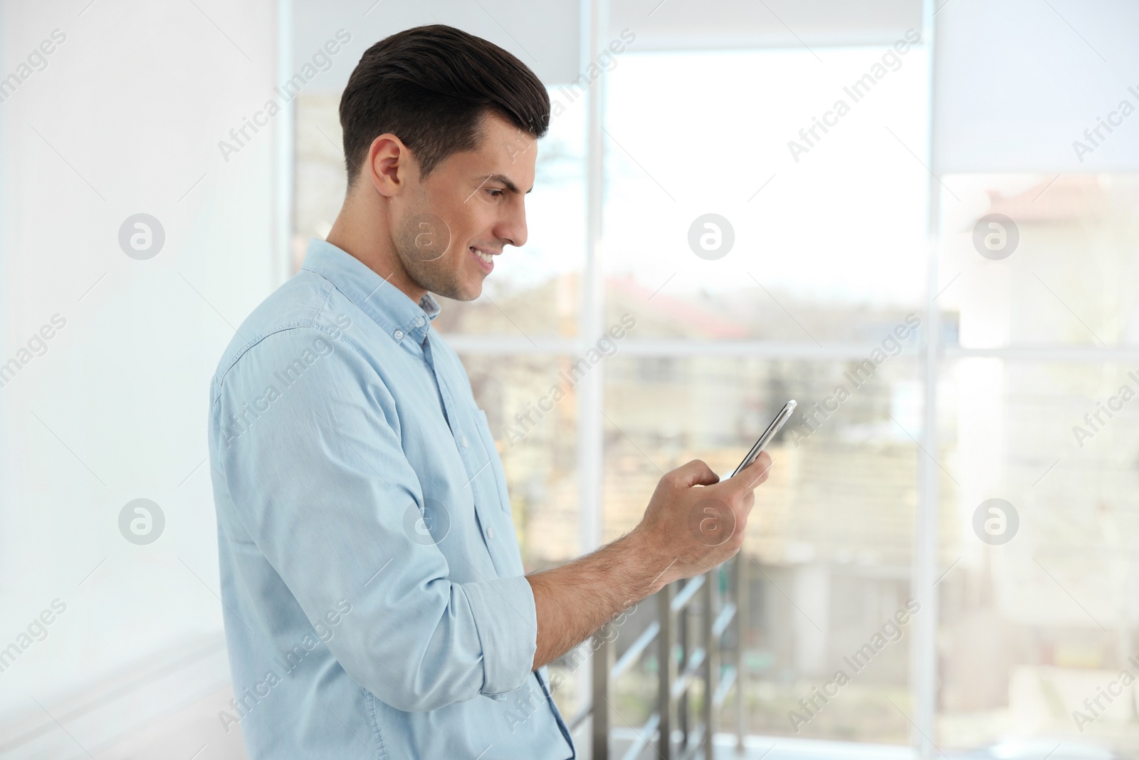 Photo of Portrait of handsome man with mobile phone in light room