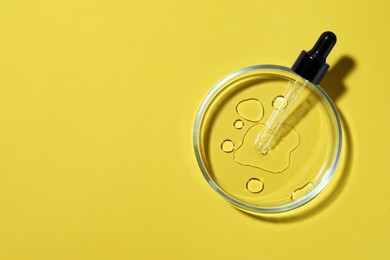 Petri dish with pipette on yellow background, top view. Space for text