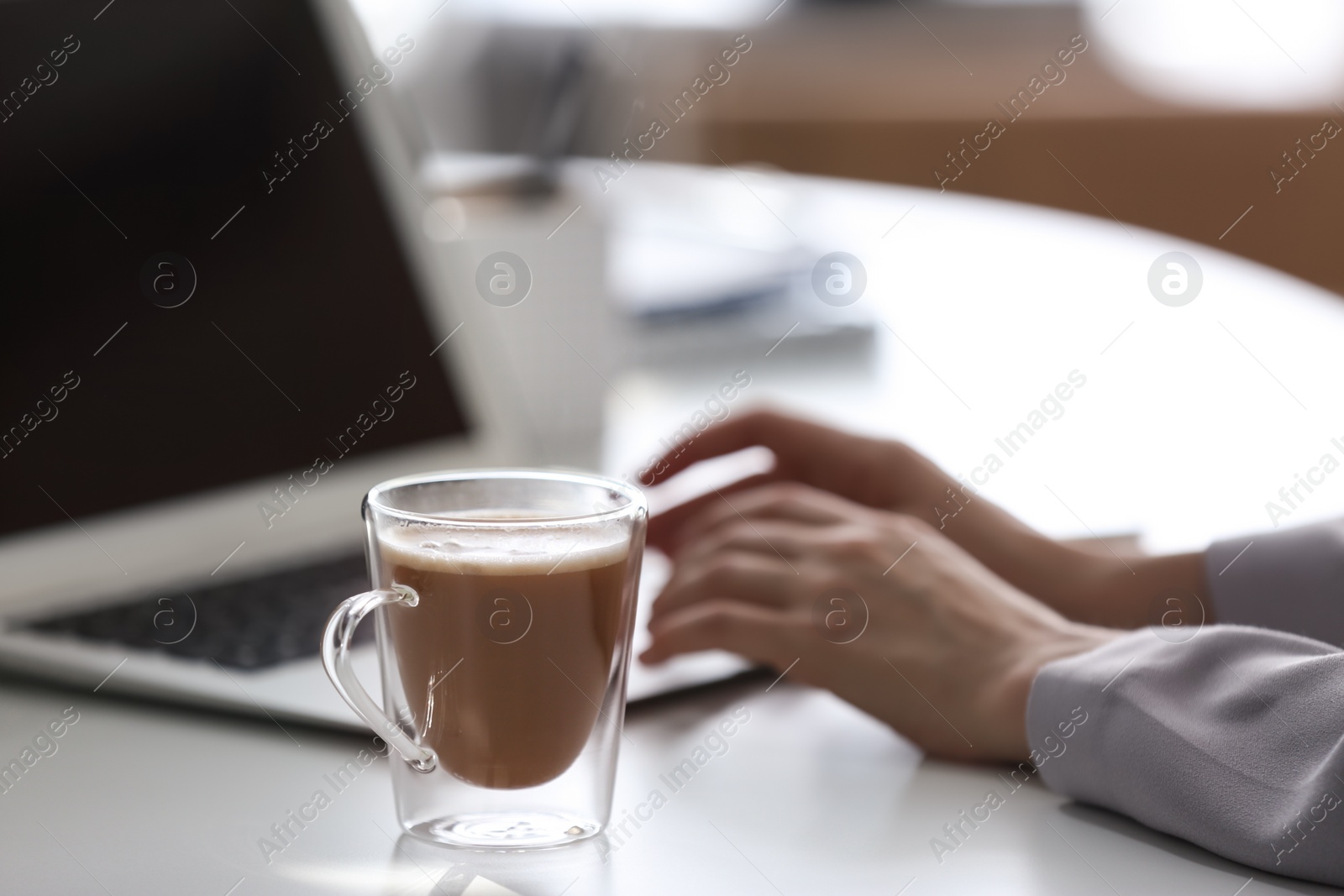 Photo of Woman with cup of coffee and laptop at table, closeup