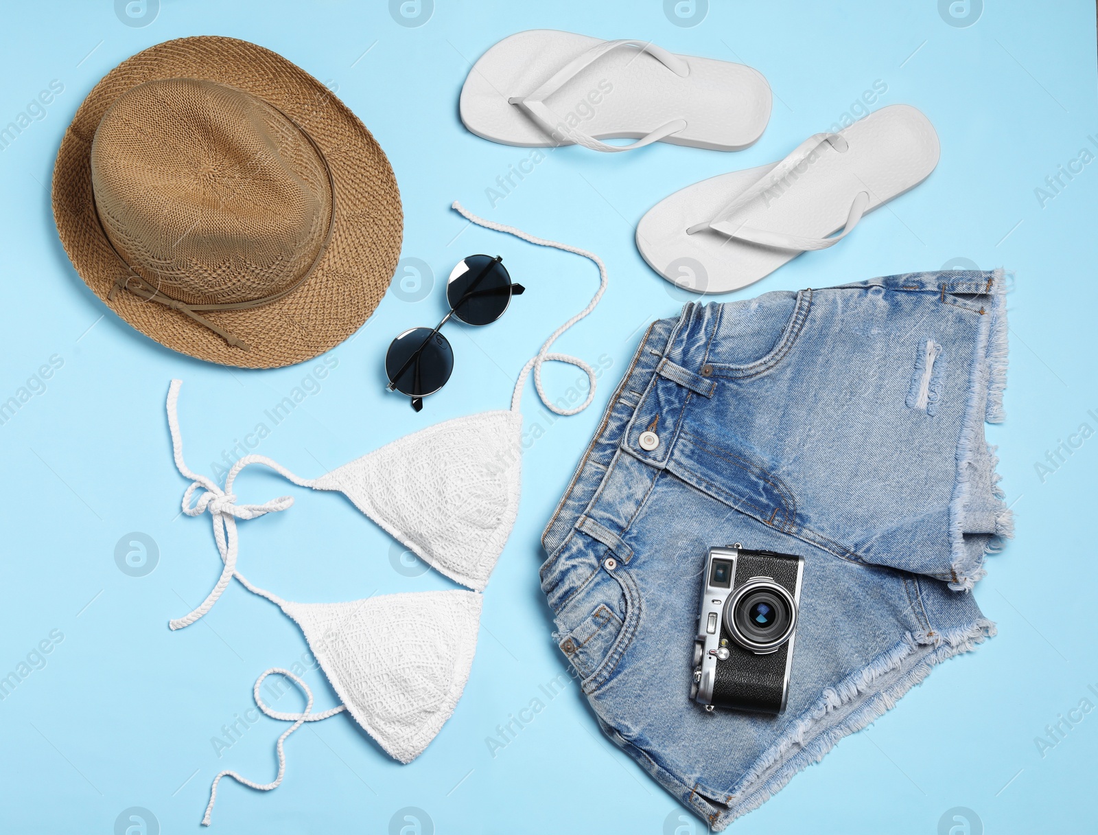 Photo of Flat lay composition with stylish beach accessories on light blue background