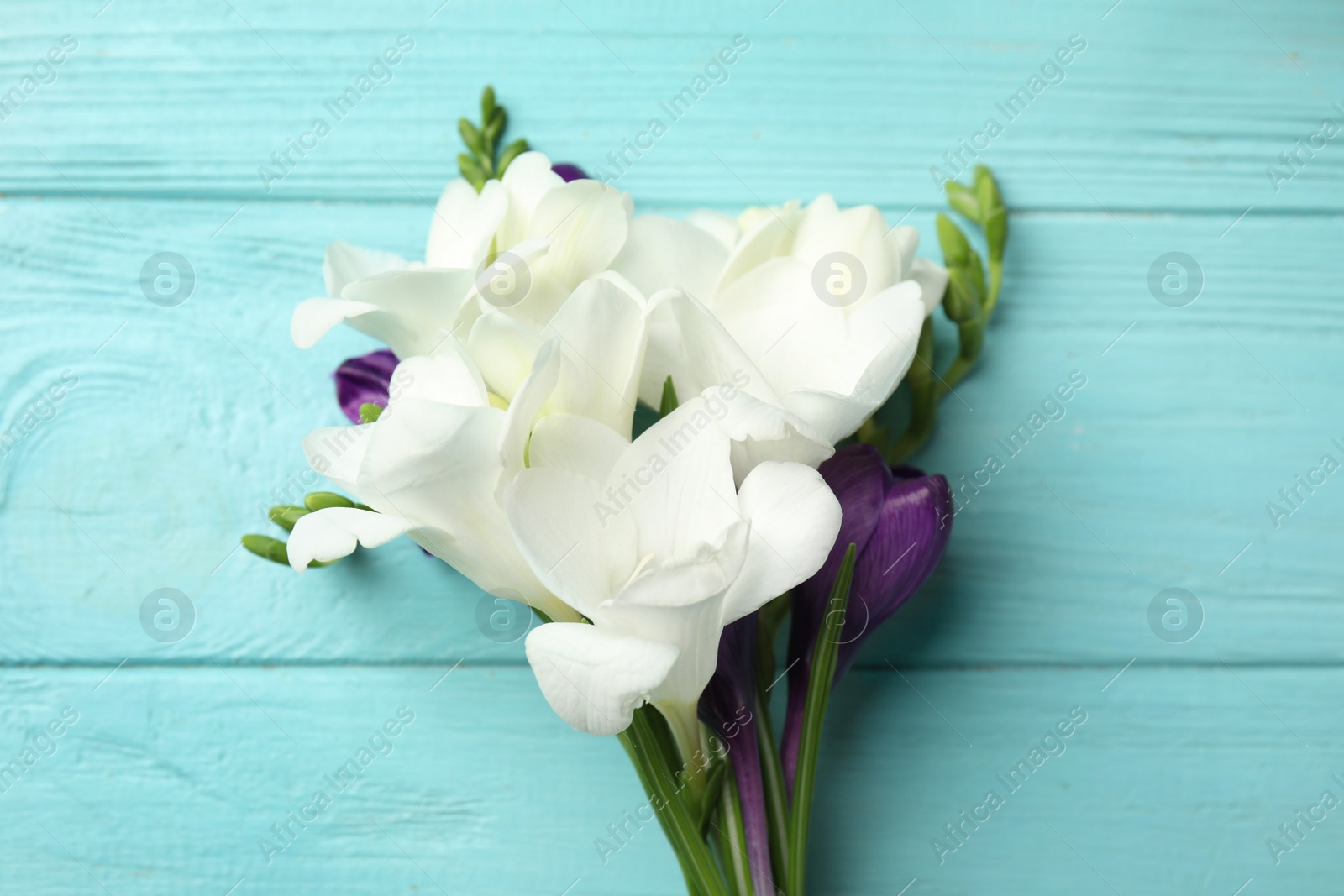 Photo of Bouquet of beautiful spring flowers on blue wooden table, top view