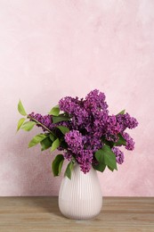 Beautiful lilac flowers in vase on wooden table