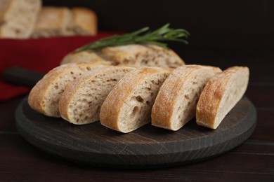 Photo of Board with cut delicious ciabatta on wooden table