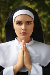 Photo of Young nun with hands clasped together praying outdoors