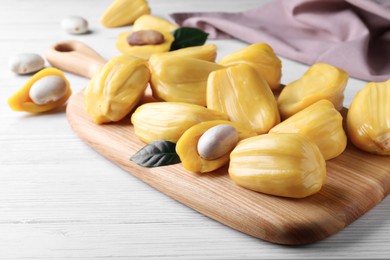 Photo of Delicious exotic jackfruit bulbs on white wooden table