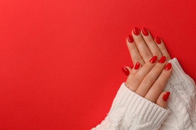 Photo of Woman with gel polish on nails against red background, top view. Space for text