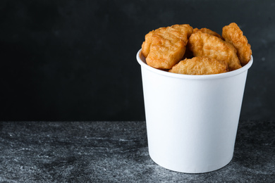 Photo of Bucket with delicious chicken nuggets on grey background. Space for text