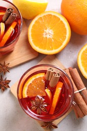 Photo of Aromatic punch drink and ingredients on light grey table, flat lay