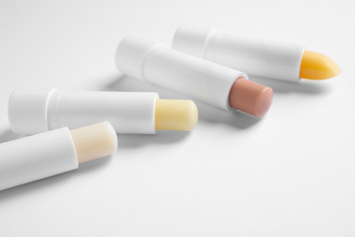 Photo of Different open hygienic lipsticks on white background