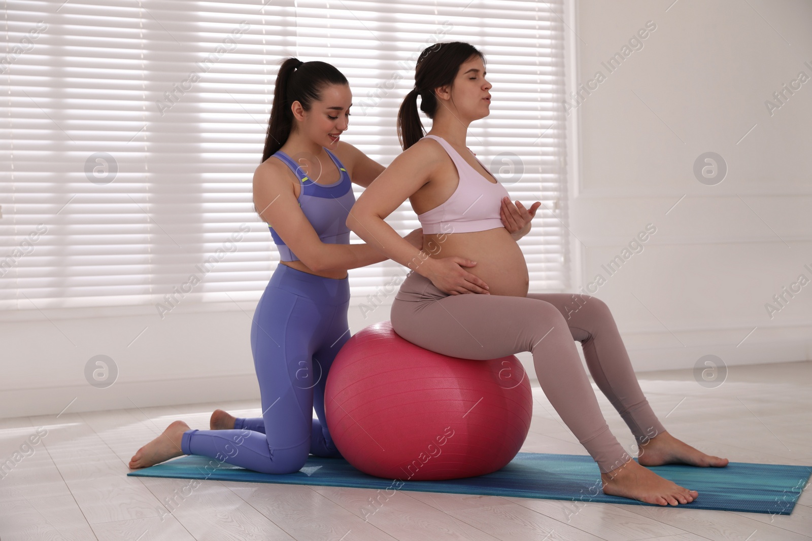 Photo of Trainer working with pregnant woman in gym. Preparation for child birth