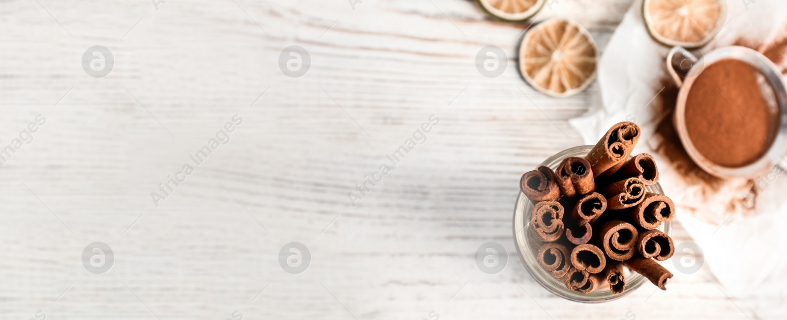 Image of Jar with aromatic cinnamon sticks on wooden background, top view with space for text. Banner design