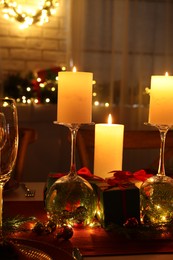 Photo of Christmas celebration. Burning candles, glasses and festive decor on table