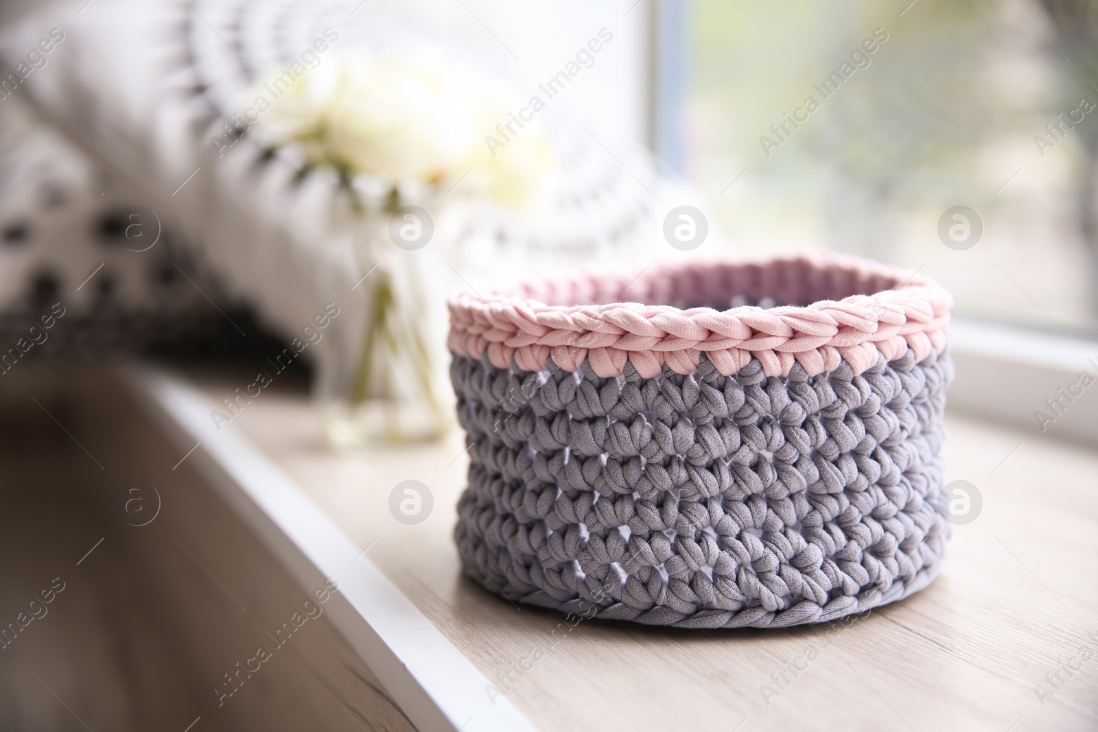 Photo of Empty knitted flowerpot cover on window sill with space for text. Interior element